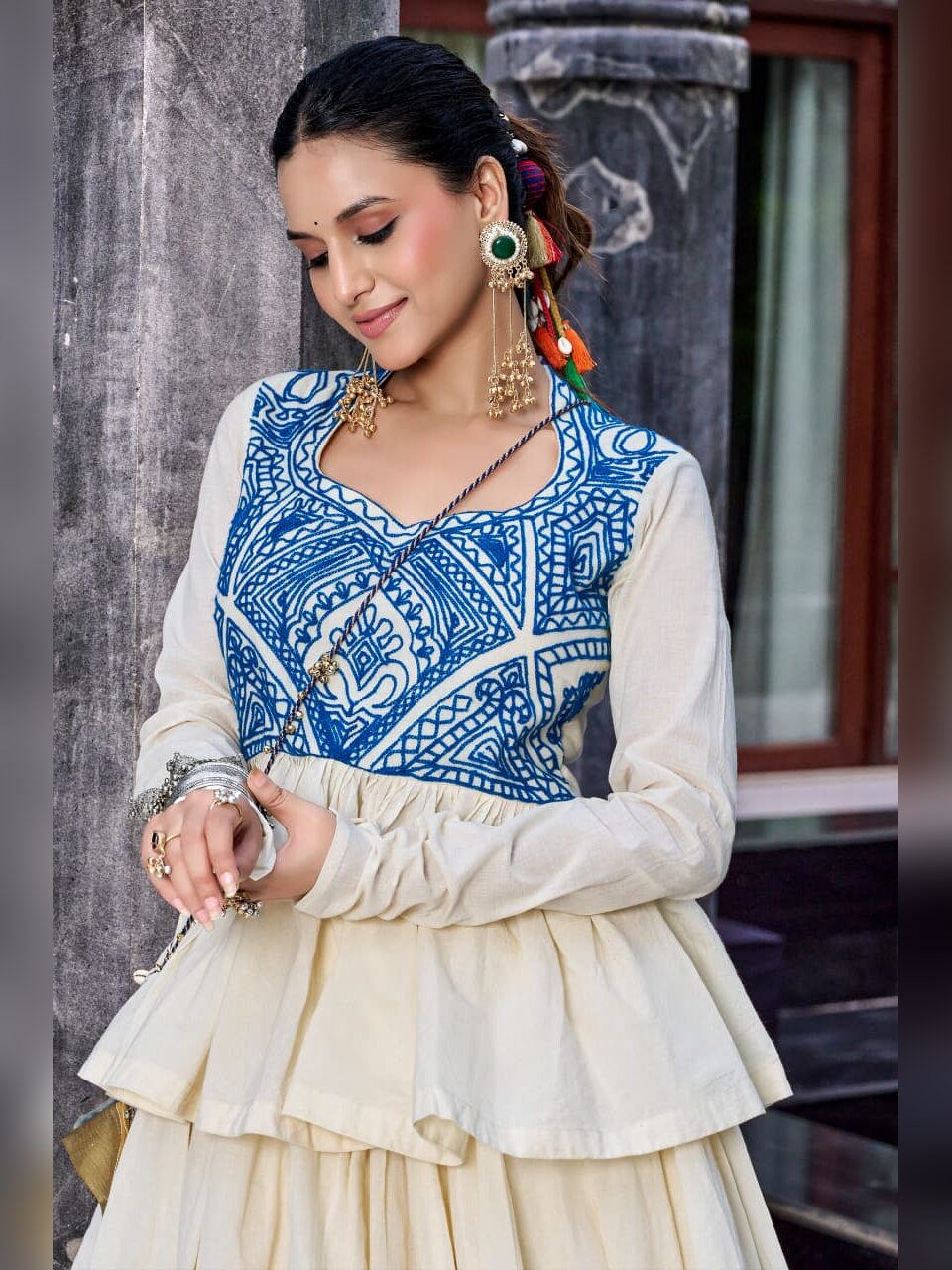 Close up of blue Kashida embroidery across the off white peplum top