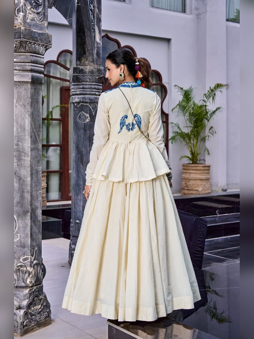 Back view showing blue parrot embroidery on the off white peplum top